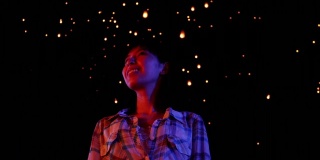 一名亚洲妇女看着天灯飞向夜空