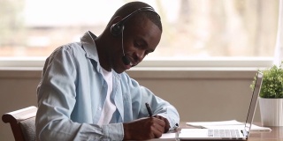 一个戴着耳机的非洲人用笔记本电脑在网上学习外语