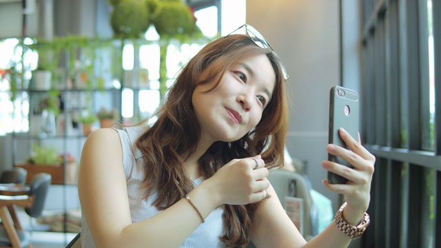 一名在咖啡店使用智能手机的亚洲女性