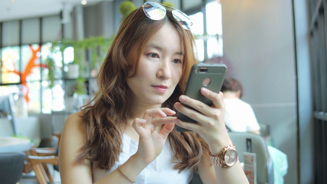 一名在咖啡店使用智能手机的亚洲女性