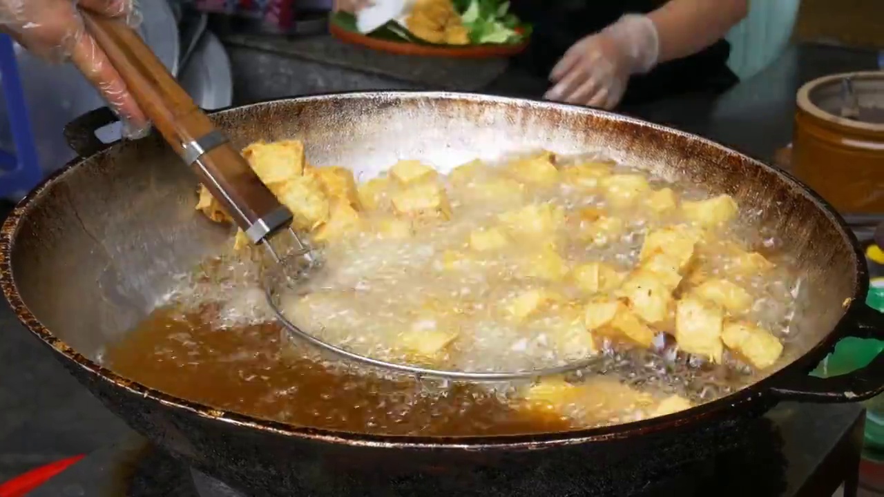 油炸豆腐在大锅或炒锅里装满油。越南街头小吃摊，垃圾食品不健康。