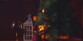 一杯葡萄酒和一棵圣诞树，背景是一个燃烧的壁炉。新年假期酗酒。酒精饮料的概念。火的背景。独自喝。餐厅的饮料。慢动作
