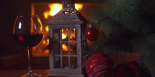 桌上放着一杯红酒，一盏圣诞灯和一棵圣诞树。背景-壁炉与火焰。新年假期酗酒。酒精饮料。火的背景。独自喝。餐厅的饮料