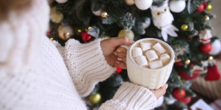 圣诞节穿着针织毛衣拿着一杯热巧克力的女人。