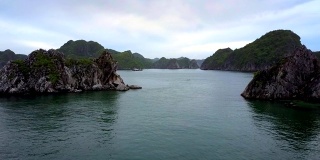 飞行摄像机靠近岩石小岛之间的蔚蓝水域