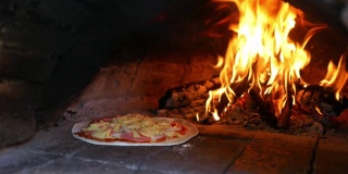 自制美味的马苏里拉奶酪披萨，在粘土烤箱中烹饪，背景是木头火焰。