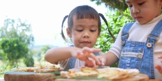 可爱饥饿的小女孩喜欢在后院吃自制的披萨。小女孩和家人在户外吃午饭。有选择性的重点。