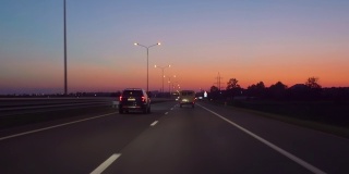 在高速公路上驾驶汽车在黑暗4K POV。傍晚日落街灯。夜，前摄像头，挡风玻璃参考。驾驶汽车POV在高速公路在夜晚在小交通后日落。