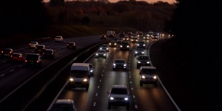 黄昏时分，高速公路上车流滚滚，汽车开着大灯。