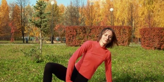 健身女性在城市秋季公园户外锻炼。体育教练在户外锻炼中进行伸展运动。瑜伽女人练习体式。