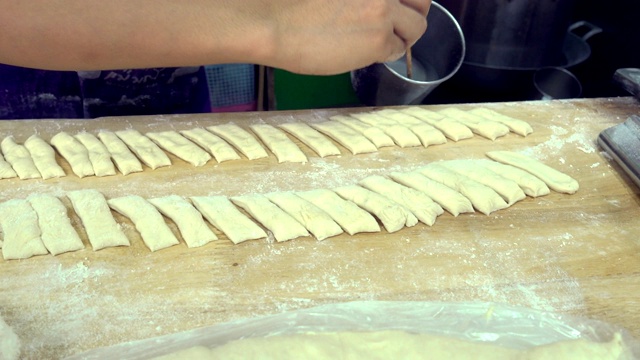 Seller hand prepare of fried bread stick, the bread is also popularly known as Cakoi, a popular Chinese cuisine.