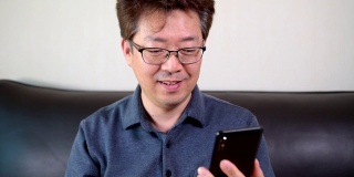 亚洲中年男子有一个愉快的视频通话使用智能手机。