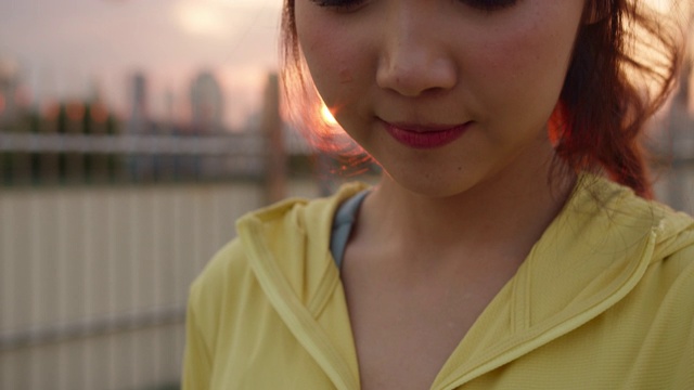 年轻的亚洲运动员女士在城市里用智能手表检查心率监测器。