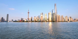 从外滩、摩天大楼和地标建筑眺望上海天际线，蓝天背景，黄浦江上平静的波涛，4k镜头，慢镜头。
