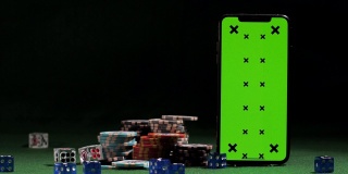 骰子落在绿色屏幕智能手机附近，游戏代币，在线赌场应用程序，获胜的机会
