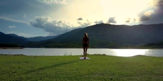 Flycam View Girl站在瑜伽姿势对着Shining River