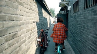 中国北京，在胡同里骑自行车的女人。视频素材模板下载