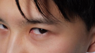 亚洲严肃可爱的人看着相机的眼睛特写。韩国男人面对4k。视频素材模板下载