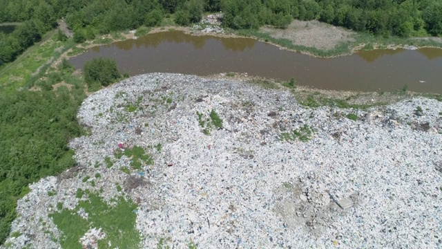 从空中俯瞰森林湖岸边的垃圾堆。