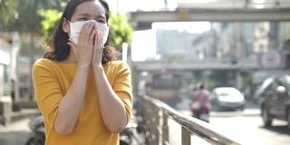 年轻的亚洲妇女咳嗽与面罩保护