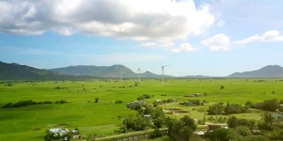无人机飞过山谷，村庄附近有风力发电站