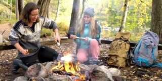女性朋友在户外露营时在篝火上做传统煎饼