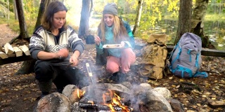 女性朋友在户外露营时在篝火上做传统煎饼