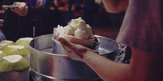 亚洲女游客在曼谷跳蚤市场享用椰子冰淇淋