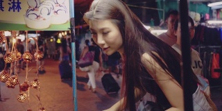 亚洲女游客在曼谷跳蚤市场享用椰子冰淇淋