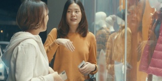 两个年轻的亚洲女人看着商店的橱窗，慢镜头