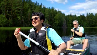 一对成年夫妇在芬兰的森林湖上划独木舟。视频素材模板下载