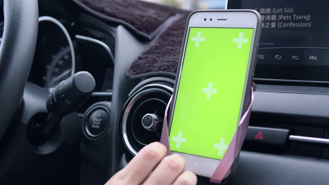女人在路上开车并使用绿屏智能手机