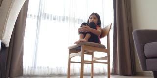 悲伤的小女孩坐在房间里的椅子上