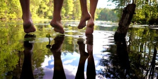 一对年轻的夫妇坐在森林湖边的木码头边享受宁静