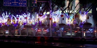 汽车在雨中行驶，车灯在画面中闪烁。大城市夜间的交通。圣诞树上的圣诞装饰品