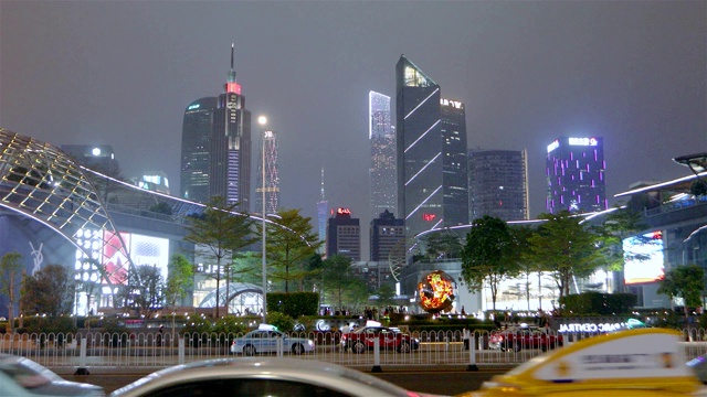 中国广州夜间道路上的交通。晚上马路上有很多车，高大的现代建筑作为背景