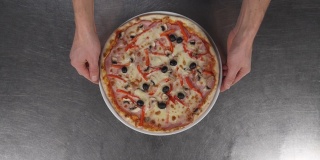 男性的手拿着一盘美味的披萨的特写。典型的意大利食物，搭配奶酪和新鲜的番茄酱。意大利美食的概念，意大利披萨餐厅的传统