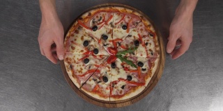 男性的手拿着一块美味的比萨饼木板的特写。典型的意大利披萨。意大利菜的概念，餐厅披萨的传统