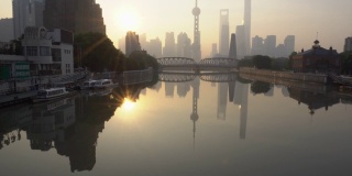 清晨宁静的上海城市天际线，外白渡桥和倒影与日出的河流，中国。倾斜了。