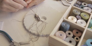生活理念，在家工作，重塑你的生活:特写细节的女人的手编织编织的宝石与一些彩色线轴前景和散景效果拍摄在平面颜色