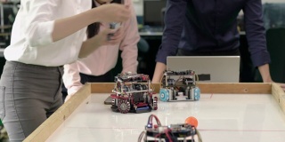 亚洲青少年年轻工程师组装和测试机器人手臂反应在实验室。建筑师设计电路，会议共享技术理念和协作开发机器人。
