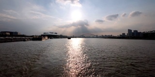 夕阳下的上海黄浦江上，大船身后的水迹与黄浦江上的上海城市地标剪影相呼应。慢镜头，4k镜头。