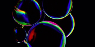 3D抽象色彩动画背景。孤立的多色球体在黑暗区域。主动旋转液体彩球。波球面光谱颜色梯度。彩虹光折射物体特写