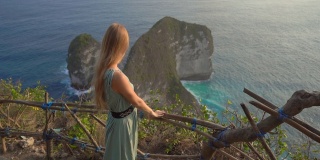 印尼努沙佩尼达克林金海滩，一名年轻的女游客正在参观所谓的霸王龙岩石。努沙佩尼达岛上著名的旅游景点。Slowmotion拍摄