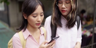两个年轻的亚洲女孩走在街上用智能手机导航