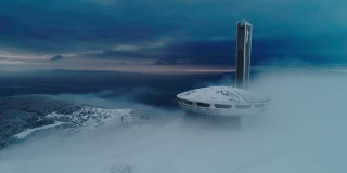 冬季鸟瞰图美丽，戏剧性，快速移动的云在雪山山顶，科幻的心情，嗡嗡扎纪念碑，不明飞行物。