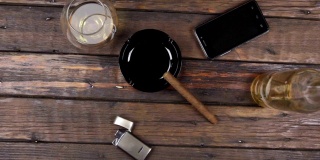 顶视图上的烟灰缸上的雪茄，一杯酒精和打火机旁边的一瓶酒精。起重机。