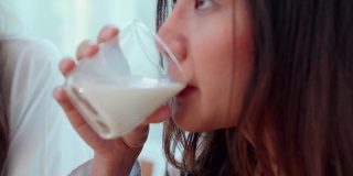 健康的年轻女子是喝牛奶和吃面包在早上出去工作。
