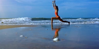 女人让瑜伽勇士在泡沫波附近的海滩上摆姿势