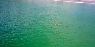 女人在海里游泳，游客在海滩上散步